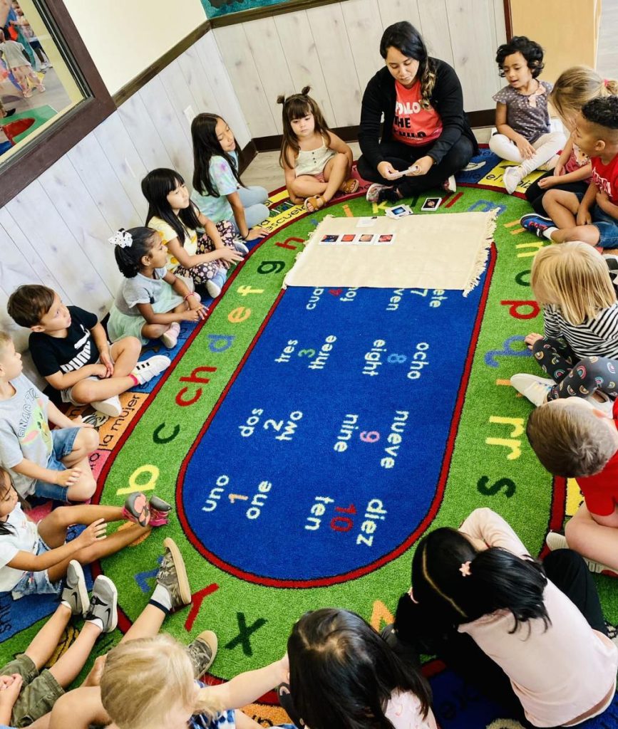 A teacher conducting a group learning session with children seated on an educational rug at Pinnacle Montessori of Castle Hills.