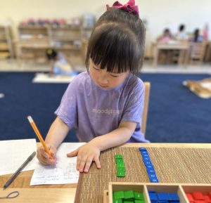 A kid at Pinnacle Montessori of Castle Hills is doing math on paper