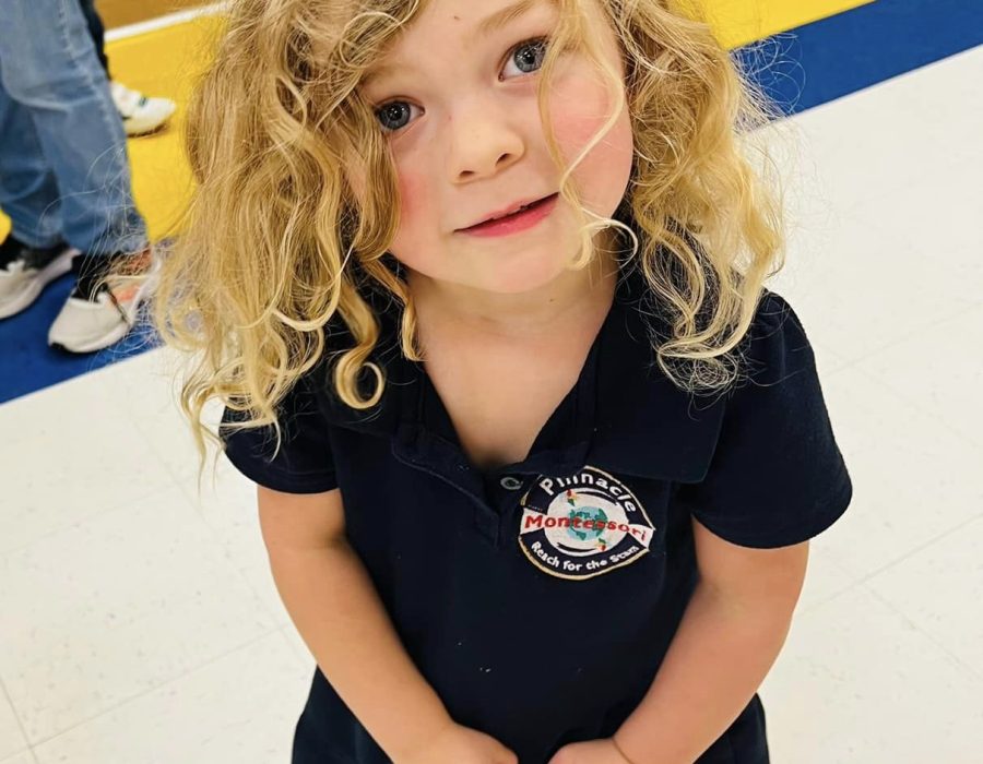 A young child from Pinnacle Montessori of Castle Hills stands with her little bag of joy.