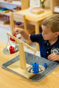 At Pinnacle Montessori of Crown Ridge, a toddler is exploring weight scaling activities