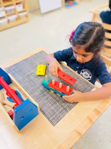 A curious student exploring Montessori materials to enhance her cognitive skills