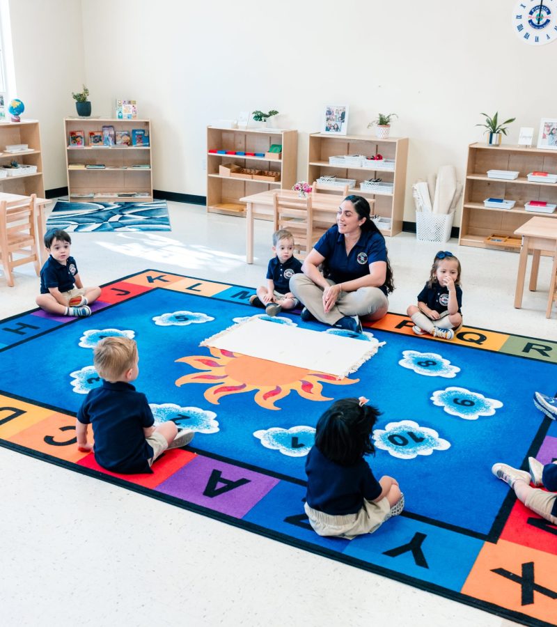 Children and teachers sharing a joyful learning moment in a warm, inviting Montessori classroom.