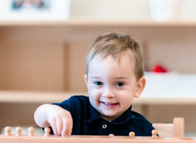 A toddler is flashing a big smile at Pinnacle Montessori of Alliance.