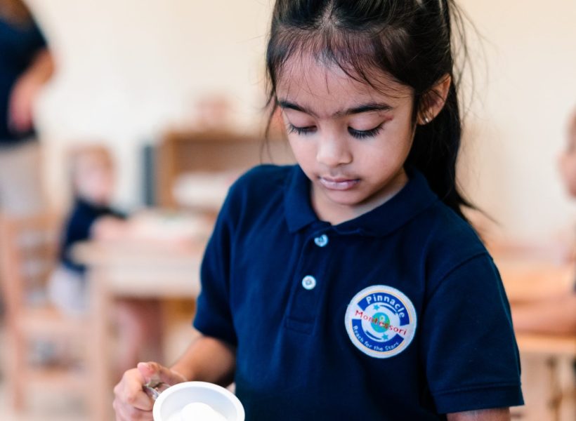 A student at Pinnacle Montessori of Alliance is pouring milk into a glass.
