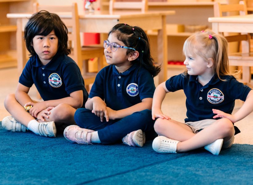 Three students at Pinnacle Montessori of Alliance are sitting together.